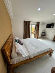 a bedroom with a large bed with white sheets and pillows at Chambre La Villa Kalanga in Abidjan