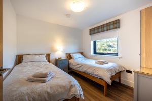 a bedroom with two beds and a window at Annabella Cottages in Crossford