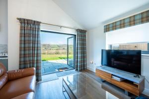 a living room with a flat screen tv and a couch at Annabella Cottages in Crossford