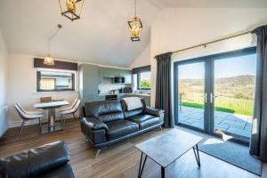 a living room with a leather couch and a table at Annabella Cottages in Crossford