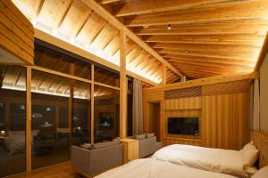 a bedroom with wooden ceilings and a bed and a tv at ヴィラブラマーレ in Kitahiroshima