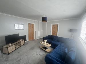 a living room with a blue couch and a tv at Grieve Apartment in Jedburgh