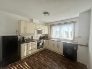 a kitchen with white cabinets and a black refrigerator at Grieve Apartment in Jedburgh