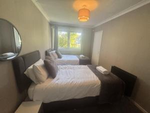 a hotel room with two beds and a window at Grieve Apartment in Jedburgh