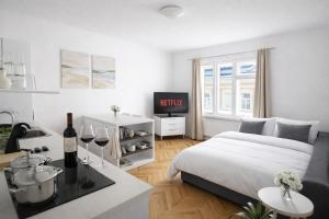 a white bedroom with a bed and a table with wine glasses at Mona Lisa Apartment in Bratislava