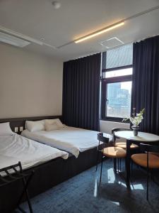 a hotel room with two beds and a table and a window at THE EXTAY Lounge Jongno in Seoul