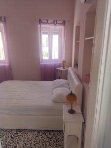 a bedroom with a white bed and a window at Angel House in Ermoupoli