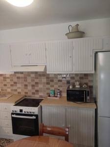 a kitchen with white cabinets and a stove and a microwave at Angel House in Ermoupoli