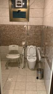 a small bathroom with a toilet and a chair at Niyaf Serviced Apartments in Khamis Mushayt +31 photos