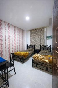 a room with two beds and a table and a desk at Coin de repôs in Oujda