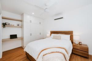 a white bedroom with a bed and a tv at The Hideaway on McFarlane, Mudgee in Mudgee