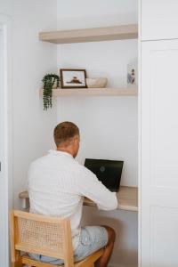 a man sitting at a desk with a laptop at The Hideaway on McFarlane, Mudgee in Mudgee