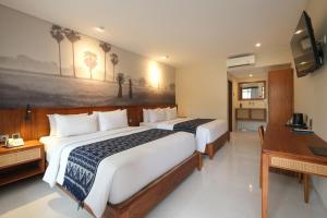 a hotel room with two beds and a desk at Matahari Bungalow in Legian