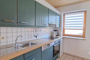 a kitchen with blue cabinets and a sink and a window at Haus 26 Natur Ferienpark - Ruhe, Natur und Komfort für erholsame Tage fern vom Alltag in Nieheim
