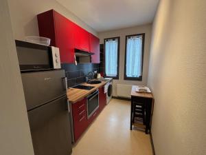 a small kitchen with red cabinets and a small table at Sur Tulle - Le Refuge - 1 Piece in Tulle