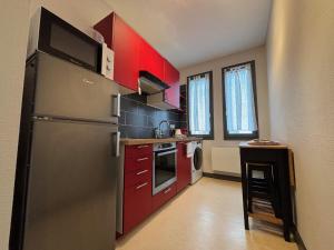 a kitchen with red cabinets and a stainless steel refrigerator at Sur Tulle - Le Refuge - 1 Piece in Tulle