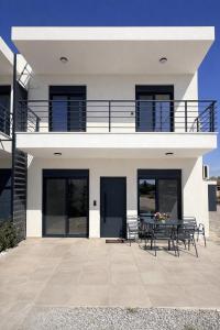 a white house with a table and chairs at Ariadne Stay Complex by Horizon Homes in Ofrínion