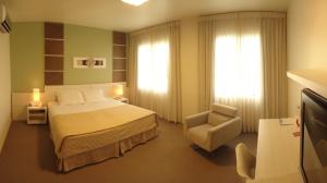 ein Hotelzimmer mit einem Bett und einem Stuhl in der Unterkunft Locanda Hotel in Novo Hamburgo