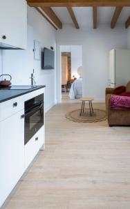 a kitchen with white cabinets and a living room at El Sueño, Paca in Barres