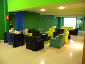 une salle d'attente avec des chaises, des tables et des murs verts dans l'établissement Nest Style Santiago, à Saint-Jacques-de-Compostelle