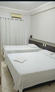 two beds in a room with white walls at Florença Hotel in Quedas do Iguacu