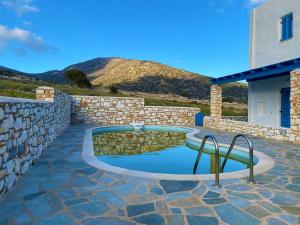 a swimming pool with a stone retaining wall and a stone wall at Villa Effie in Aspro Chorio Paros