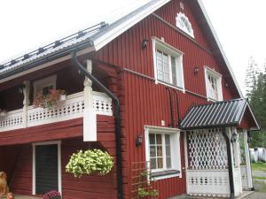 a red house with a white balcony and a window at Yli-Kaitala Holiday Resort Tuuliviiri in Savio +5 photos