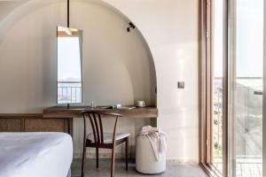 a bedroom with a desk and a bed and a window at Casa Elounda - Adults only Hotel "by Checkin" in Agios Nikolaos