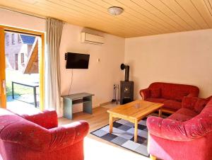 a living room with two red couches and a table at Haus 25 im Natur Ferienpark, Erlebnisurlaub mit Action, Radfahren und Wanderabenteuern im Grünen in Nieheim