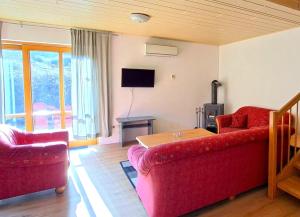 a living room with two red couches and a table at Haus 25 im Natur Ferienpark, Erlebnisurlaub mit Action, Radfahren und Wanderabenteuern im Grünen in Nieheim