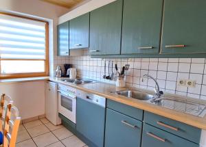 a kitchen with blue cabinets and a sink at Haus 25 im Natur Ferienpark, Erlebnisurlaub mit Action, Radfahren und Wanderabenteuern im Grünen in Nieheim