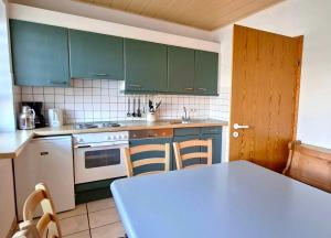 a kitchen with green cabinets and a blue table at Haus 25 im Natur Ferienpark, Erlebnisurlaub mit Action, Radfahren und Wanderabenteuern im Grünen in Nieheim +16 photos