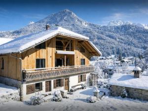 a log house in the snow with mountains in the background at La Grange Neuve - OVO Network in Saint-Jean-d'Aulps