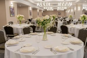 a banquet room with white tables and chairs with white flowers at Yevlakh City Hotel in Yevlax