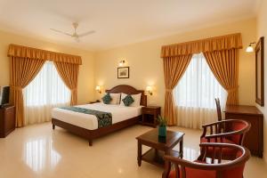 a hotel room with a bed and a table and chairs at Hotel Indraprastha Thiruvalla in Talavadi +34 photos