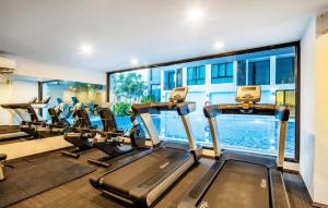 a gym with cardio equipment and a swimming pool at Therizinpattaya in Pattaya South