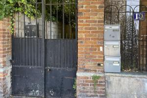 an entrance to a brick building with a gate and an old refrigerator at L'Éclipse - Gare de Melun in Melun