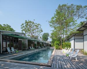 a swimming pool with white chairs next to a building at The Stage-Koh Chang in Ko Chang