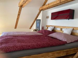a bedroom with a wooden bed with red sheets at Apartmán Ateliér in Bílé Vchynice