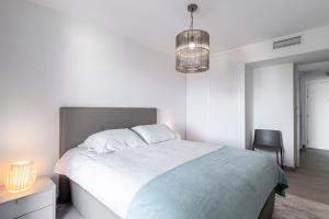 a white bedroom with a large bed and a chandelier at Victoria Palace- l'appartement avec vue mer et à proximité de Monaco in Beausoleil