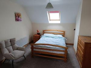 a bedroom with a bed and a chair at 4 Bed Close to Beach and Village in Enniscrone