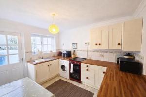 a kitchen with white cabinets and a washer and dryer at Pen Llyn Quarryman's Cottage in Trevor