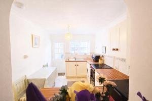 a kitchen with white cabinets and a table with flowers at Pen Llyn Quarryman's Cottage in Trevor