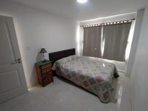a bedroom with a bed and a window and a nightstand at Complejo EyE in General Roca +2 photos