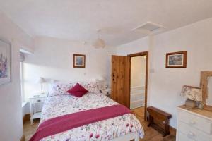 a bedroom with a bed with a red pillow on it at Pen Llyn Quarryman's Cottage in Trevor