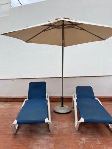 two blue chairs and an umbrella in a room at Close to the beach duplex in Tossa de Mar