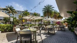 an outdoor restaurant with tables and chairs and umbrellas at Angler's Hotel - Miami Beach in Miami Beach