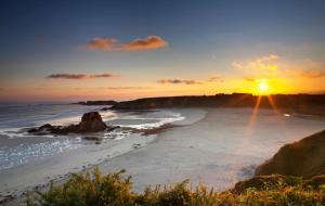 a sunset on a beach with the sun setting at El Sueño, Pilaro in Barres