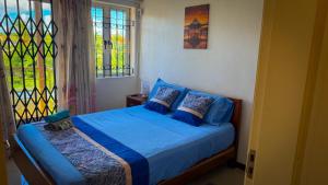 a bedroom with a bed with blue sheets and a window at The Aviators Villa in Flic-en-Flac +18 photos