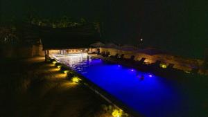 a swimming pool lit up at night with blue lights at Duli Beach Farm Hostel in Duli